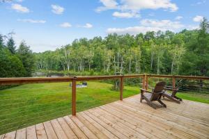 a wooden deck with a chair and a view of a field at Chalet au Bord de l'Ecluse in Brébeuf +25 photos