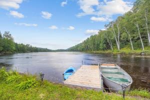 a boat parked next to a dock on a river at Chalet au Bord de l'Ecluse in Brébeuf