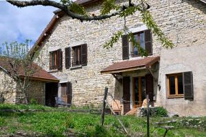 an old stone house with two chairs in front of it at Gîte à l'origine in Montgesoye
