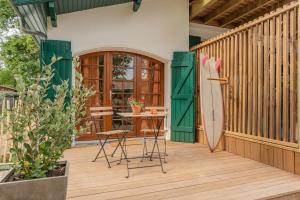 a patio with a green door and a table and a surfboard at Brume Surf House in Messanges