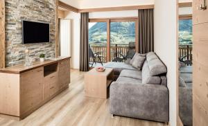 a living room with a couch and a tv at Nutzhof - Mediterran Flair Hotel in Lagundo