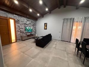 a living room with a black couch and a stone wall at Complejo Rural Santa Emma in Herencia