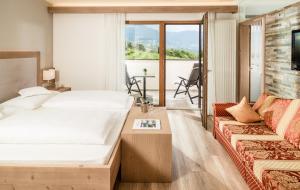 Habitación de hotel con cama y sofá en Nutzhof - Mediterran Flair Hotel en Lagundo