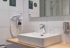 a bathroom with a white sink and a mirror at B&B HOTEL Brumath Bernolsheim in Brumath
