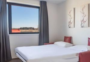 two beds in a room with a window at B&B HOTEL Brumath Bernolsheim in Brumath