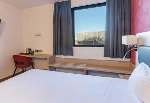 a room with a bed and a desk and a window at B&B HOTEL Brumath Bernolsheim in Brumath