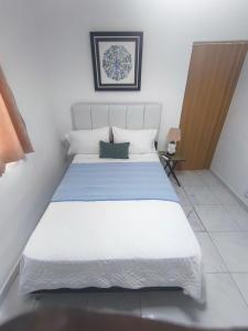a bedroom with a large white bed with white pillows at Hostal Dermari in La Romana