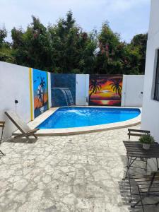 a swimming pool with a bench and paintings on the wall at Hostal Dermari in La Romana