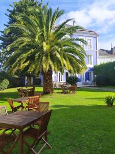 a palm tree in a park with a table and benches at Hotel La Balastrera in Ribadeo