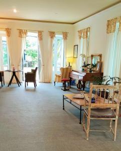 a living room with a piano and chairs and windows at Hotel La Balastrera in Ribadeo