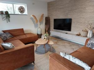 a living room with two couches and a flat screen tv at Duinvilla Wetterwille met sauna in Makkum
