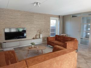 a living room with a couch and a tv at Duinvilla Wetterwille met sauna in Makkum