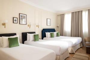 two beds in a hotel room with green accents at Hotel Du Flaneur in Paris
