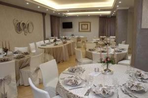 a banquet room with white tables and white chairs at Sammartano Hotels in Marsala