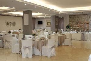 a banquet hall with white tables and white chairs at Sammartano Hotels in Marsala
