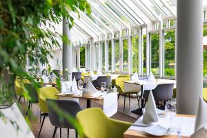 a restaurant with tables and chairs in a greenhouse at relexa hotel Bad Steben in Bad Steben
