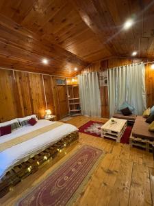 a bedroom with a large bed in a room with wooden walls at Tirthan Chalet in Kulu