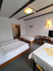 ein Zimmer mit zwei Betten, einem Schreibtisch und einem Fernseher in der Unterkunft Hotel Nöhre in Wittingen