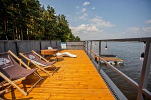 a wooden dock with chairs and a table on the water at Nad Narvią in Serock