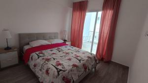 a bedroom with a bed and a window with red curtains at One suite los corales in Punta Cana