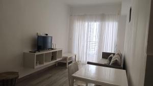 a white living room with a table and a tv at One suite los corales in Punta Cana