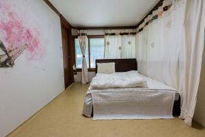 a bedroom with a bed with white sheets and a window at Najoo sunflowerstay in Naju