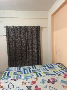 a bed with a comforter and a curtain in a bedroom at Suyakshi homestay in Pune