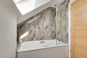 a bathroom with a bath tub with a stone wall at 4 Bed in Steeple Bumpstead oc-hatch in Steeple Bumpstead +35 photos