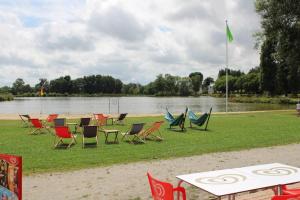 a group of chairs and tables next to a lake at Gîte Beaulieu à Combrée in Combrée