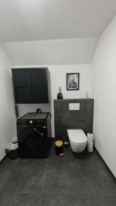 a bathroom with a toilet and a flat screen tv at La Petite Auberge de Graux in Mettet