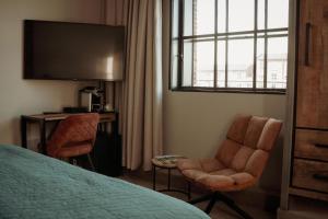 a bedroom with a bed and two chairs and a window at Boutique Hotel De Oude Veste in Hellevoetsluis