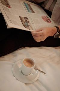 a person reading a newspaper with a cup of coffee at Boutique Hotel De Oude Veste in Hellevoetsluis