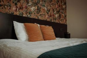 a bed with orange pillows and a floral wall at Boutique Hotel De Oude Veste in Hellevoetsluis