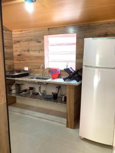 a kitchen with a sink and a white refrigerator at Chalé Damata in Ubatuba +14 photos