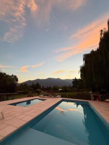 a large swimming pool with a sunset in the background at Cabaña Suiza in Cacheuta