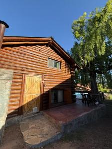 a log cabin with a patio and a tree at Cabaña Suiza in Cacheuta