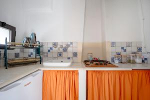 a kitchen with an orange curtain on the counter at Domus Magistri in Ostuni +20 photos