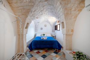 a bedroom with a blue bed in a stone wall at Domus Magistri in Ostuni