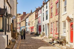 a couple of people walking down a cobblestone street at Host & Stay - Sea Haven in Staithes