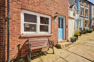 a bench in front of a brick building with a window at Host & Stay - Sea Haven in Staithes