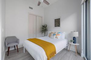 a white bedroom with a bed and a chair at South Downtown Condo no.308 in Dallas