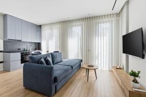 a living room with a blue couch and a kitchen at Le Mom Apart Hotel in Berat