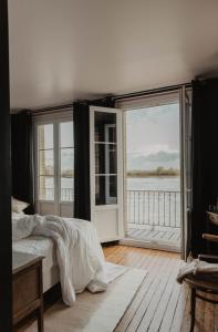 a bedroom with a bed and a view of the water at La Maison Plûme in Villequier