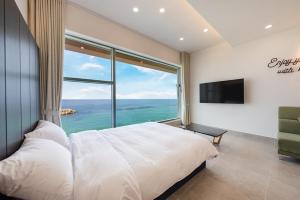 a bedroom with a large bed and a large window at Sokcho 828 Spa Pension in Sokcho