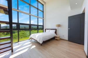 a bedroom with a bed and a large window at Goseung Poolhouse Poolvilla 151 in Goseong +17 photos