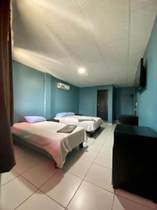two beds in a room with blue walls at Hotel Confort in Guayaquil