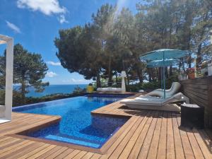 a swimming pool with a deck and an umbrella at El Desmai in San Pol de Mar