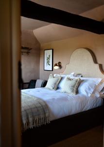 a bedroom with a large bed with white sheets and pillows at Botley Hill Farmhouse in Warlingham