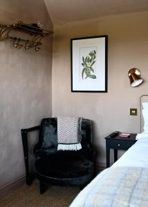 a bedroom with a black chair next to a bed at Botley Hill Farmhouse in Warlingham
