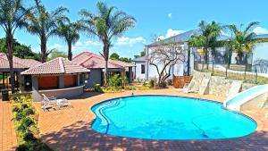 a swimming pool in front of a house with palm trees at Ultimate Sky-2 bedroom villa in Pretoria
